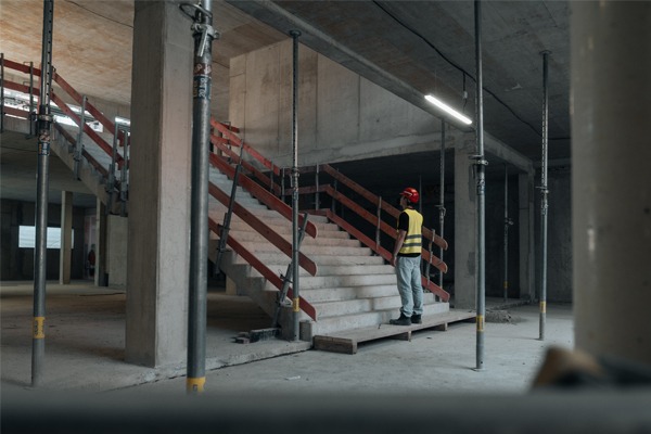 Ein Mann steht vor einer Treppe im Rohbauzustand