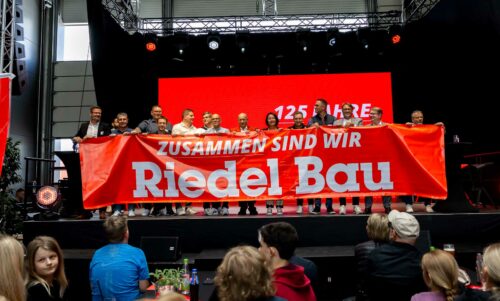 Gruppe hält Banner mit Aufschrift: Zusammen sind wir Riedel Bau